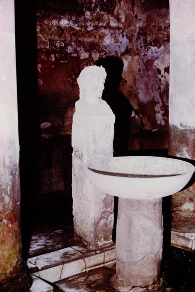 Suburban baths, Herculaneum, 1975. Atrium with fountain bust of Apollo.
Photo by Stanley A. Jashemski.   
Source: The Wilhelmina and Stanley A. Jashemski archive in the University of Maryland Library, Special Collections (See collection page) and made available under the Creative Commons Attribution-Non Commercial License v.4. See Licence and use details. J75f0721